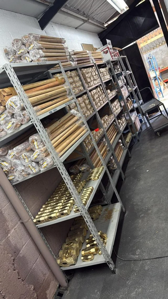 Prateleiras do estoque CUBEX com cabeças de marreta em bronze e cabos de madeira embalados.