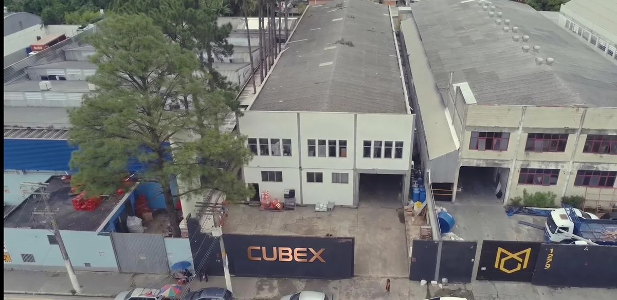 Vista aérea da sede da CUBEX em São Paulo: dois galpões e o portão com o letreiro CUBEX.